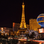 The las vegas strip at night with the eiffel tower in the background.