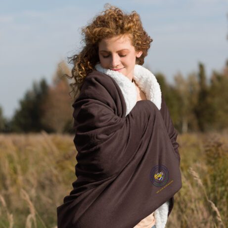 A woman in a Premium Sherpa Blanket standing in a field.
